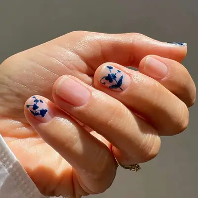 Nude manicure with French toile design in blue on every other finger.