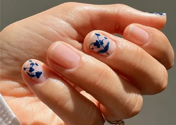 Nude manicure with French toile design in blue on every other finger.
