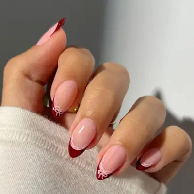 Burgundy french tips with bows manicure.