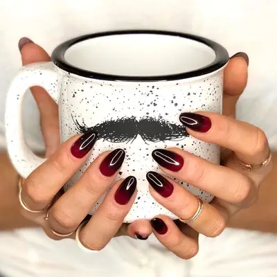 Red and black ombre nails holding mustache coffee mug
