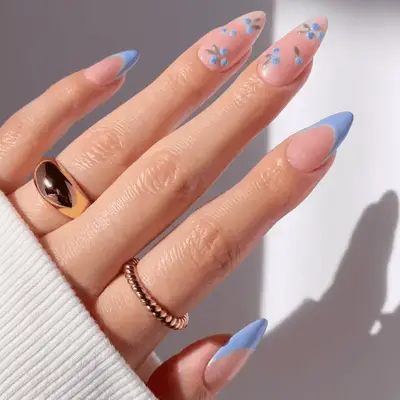 Manicure with pastel blue base and accent nails with cream base and blueberry designs