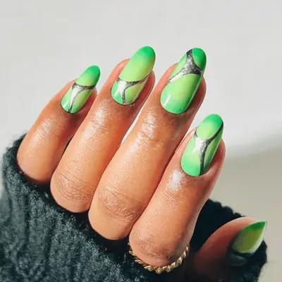 a green aura manicure topped with silver chrome webs