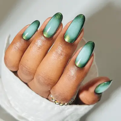 a metallic green manicure with blue auras in the middle