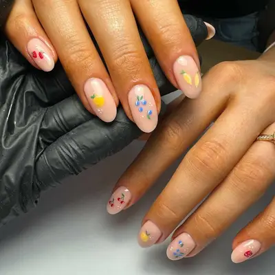 Close-up of manicure with neutral base and assorted fruit designs