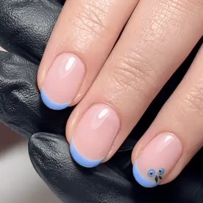 A hand displaying colorful nail art with various patterns and designs, wearing a ring on the middle finger