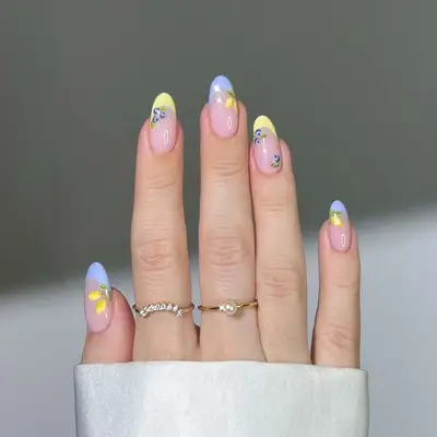 Manicure with pastel yellow and blue French tips and blueberry and lemon designs