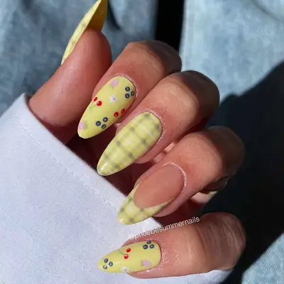 Pastel yellow manicure with berry designs and pastel plaid pattern on full nail and French tips