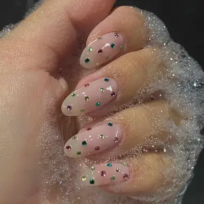 close up of nails covered in bubbles, nails have light pink base with rhinestones in every color dispersed throughout