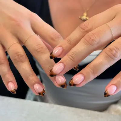 close up of manicure with nails in clear pinky base and tortoiseshell french tips