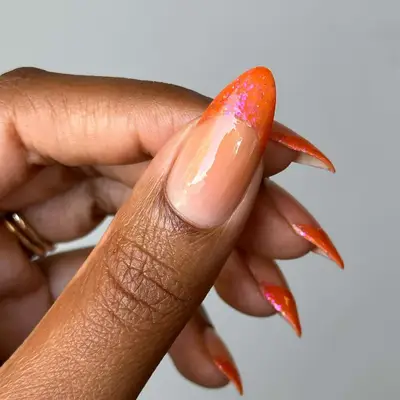 Close-up of a hand with long pointed nails colored with an orange design