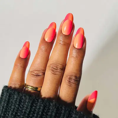 A hand wearing a dark sweater with multicolored polished nails