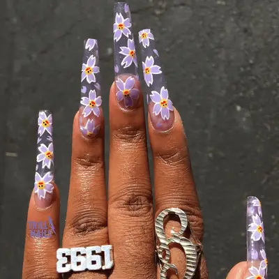 A close up of long square nails featuring purple versions of Takashi Murakami