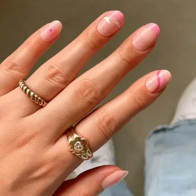Close up of mismatched nails including pink flowers, white clouds, and french tips.