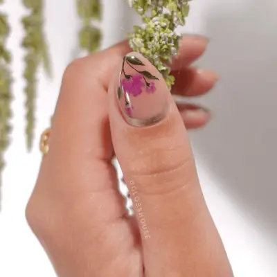 A close up of a thumb fingernails with handpainted pink floral art. 