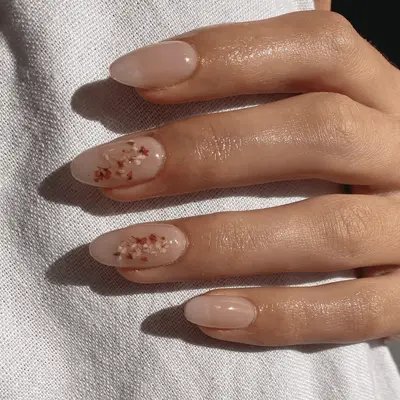 Nude manicure with dainty pressed flowers on the middle and ring finger nails