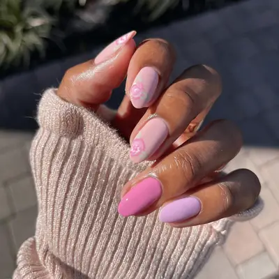 A close up of mismatched pink nails with handpainted white and pink flowers.