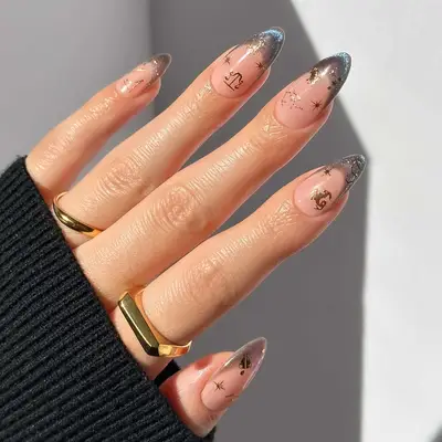 Close up of a manicure with velvet tips and zodiac decals on the natural-colored base