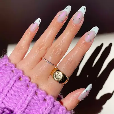 French manicure with iridescent base, white tips, and small rhinestone studs