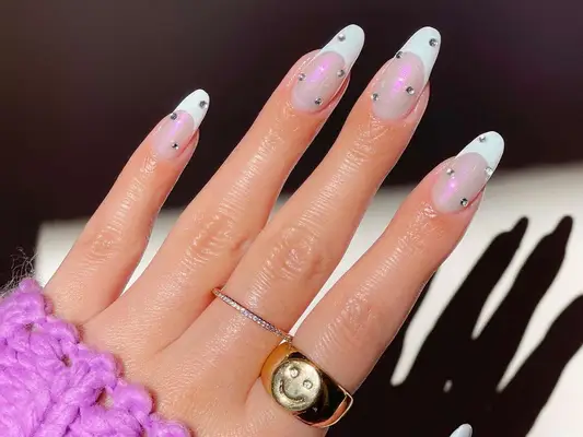 French manicure with iridescent base, white tips, and rhinestone studs