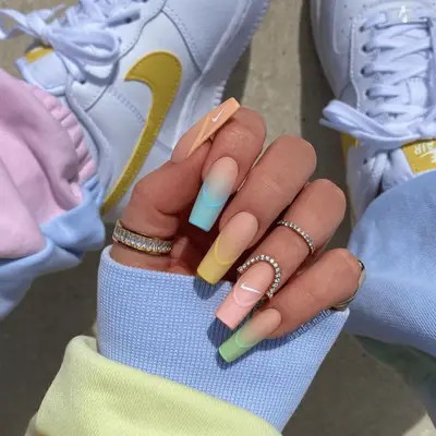 Pastel long square nails with diamond rings and Nike sneakers