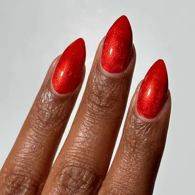 Close up of a shimmery red manicure with an orange shift