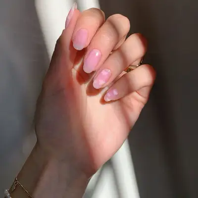 A translucent baby pink manicure with cloud designs