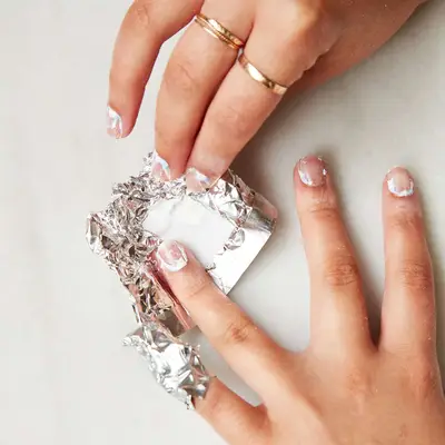 Woman removes foil and acetone cotton from a fingernail 