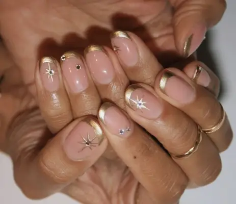 Nude nails with gold tips and starburst designs