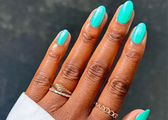 Hand with gold rings and bright teal nails