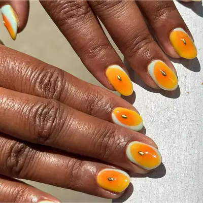 rounded orange nails with cream trim and gold accent 