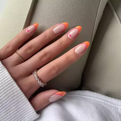 shimmer orange round tips with neon pink trim and small heart accents