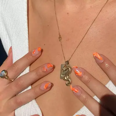 almond nail extensions with orange marble design with negative space