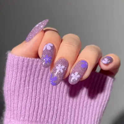 A purple glitter/velvet manicure with flower details