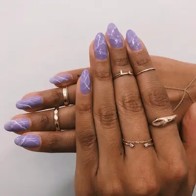 Purple marble nails on a hand with many pretty rings