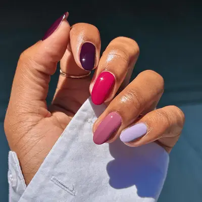 Close up of nails with alternative, tonal shades of purple on each finger.