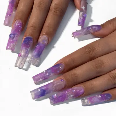 Close up of long square nails with purple swirls and galaxy print.
