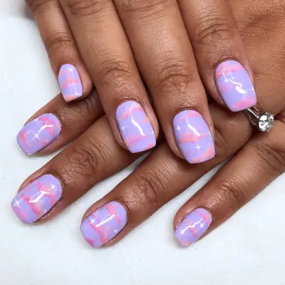 Close up of short nails with purple, white and pink clouds.