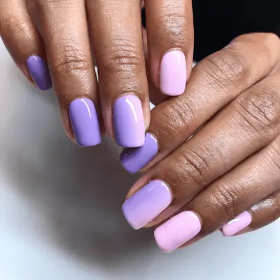 A close up of short nails painted pink and purple ombre.
