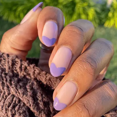 Close up of a French manicure with heart-shaped purple tips