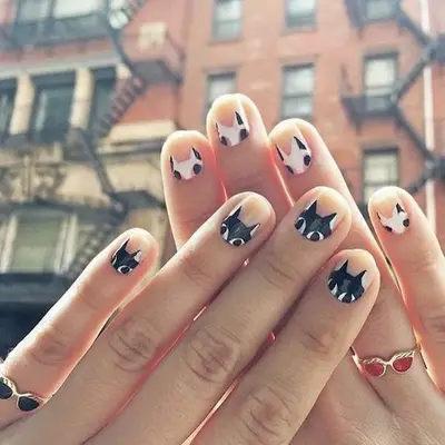 Nude nails with black-and-white cat designs at the cuticle