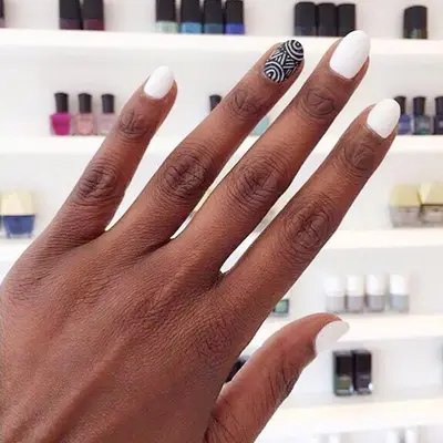 Rounded white nails with a statement black nail design at the ring finger