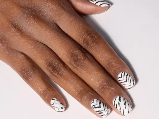 A hand with black and white zebra print nails