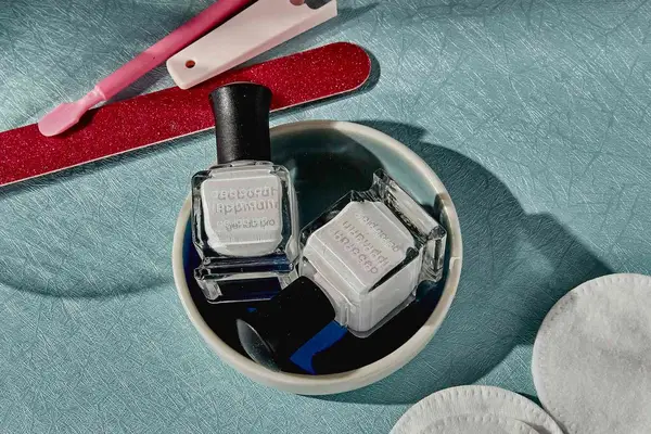 Deborah Lippmann Gel Lab Pro displayed on a blue cloth next to a nail file, cotton rounds, and other bathroom accessories