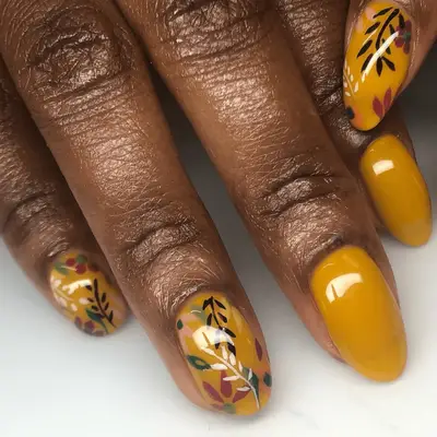 Close up of mustard yellow oval nails with fall foliage nail art.