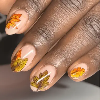 Close up of nude nails with orange leaf deisgns.