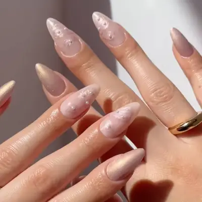 Hands showcasing manicured nails with neutral-toned designs and embellishments