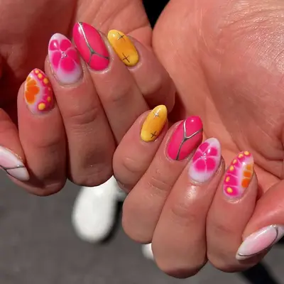 Hands with colorful gel nail art featuring floral and abstract patterns