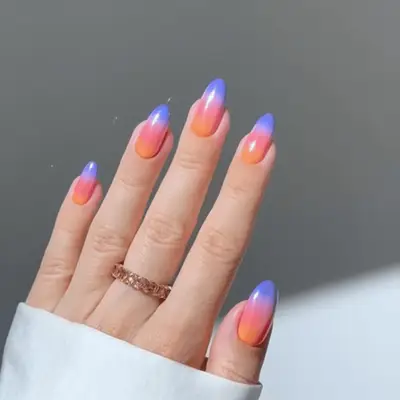 Hand showcasing metallic blue 3D manicure nails with rings