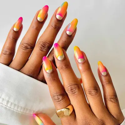 Hands with gradient sunset-themed nails and gold accents