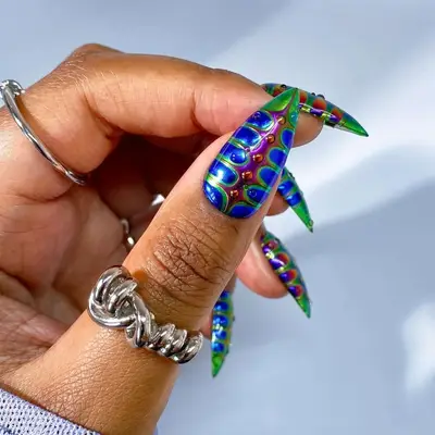 A hand with long multicolored nails featuring intricate bug-inspired designs